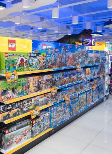 Brightly lit interior of ToysRUs, showcasing extensive shelves filled with LEGO sets and other popular toys.