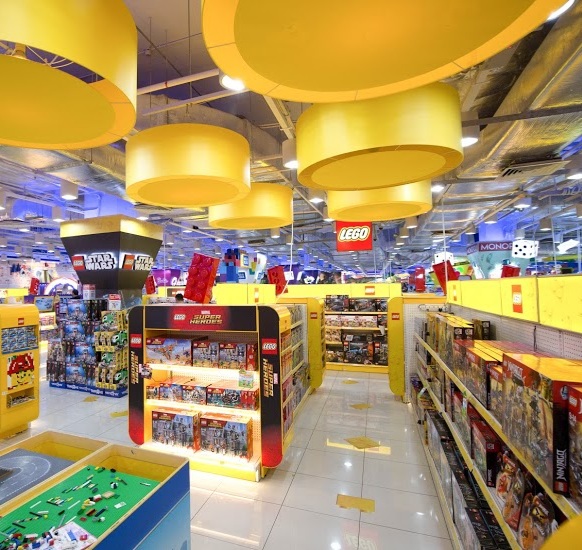 Brightly lit interior of ToysRUs, showcasing extensive Lego displays and various toy sections.