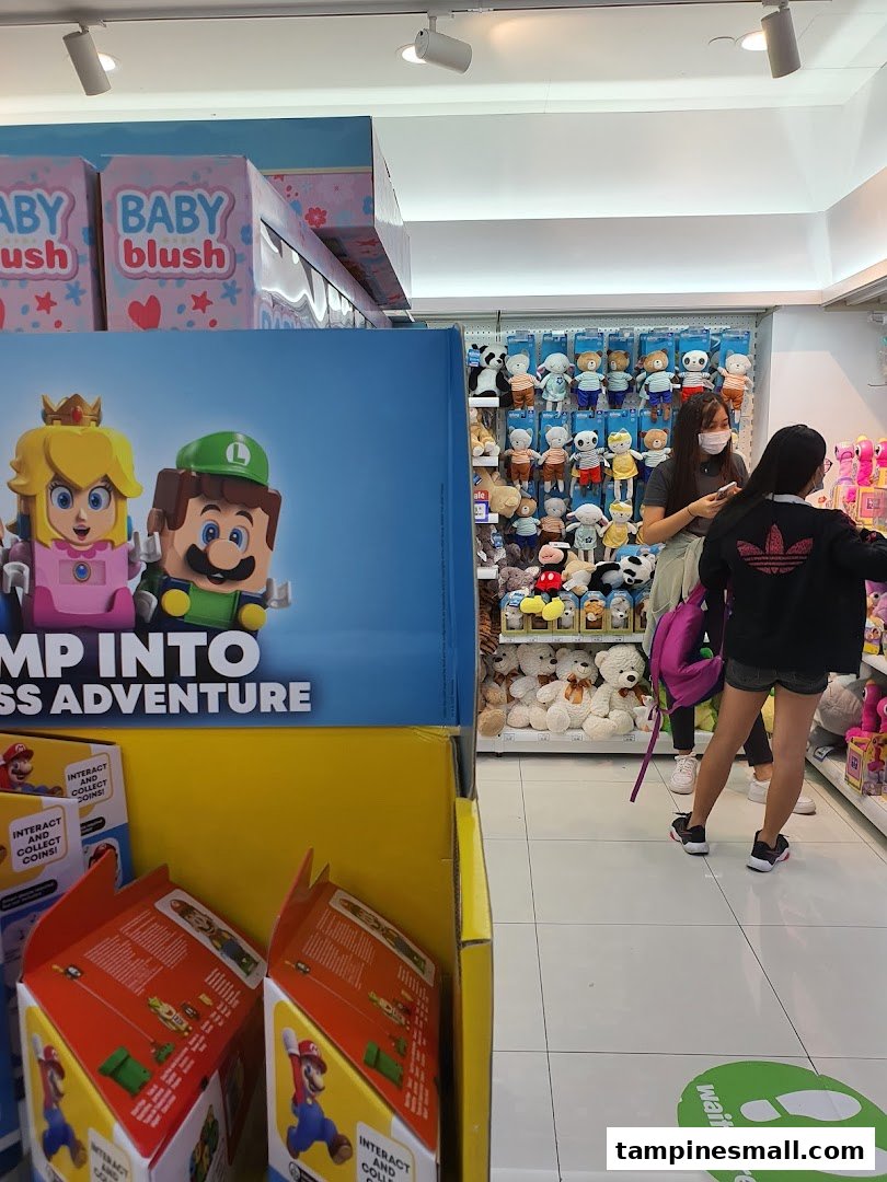 An aisle at ToysRUs featuring Super Mario displays, plush toys, and shoppers exploring the wide selection.