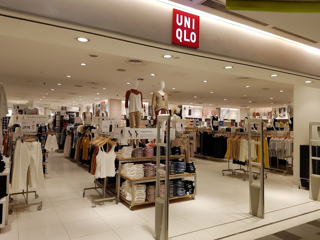 A brightly lit interior view of UNIQLO, showcasing various apparel on racks and mannequins.