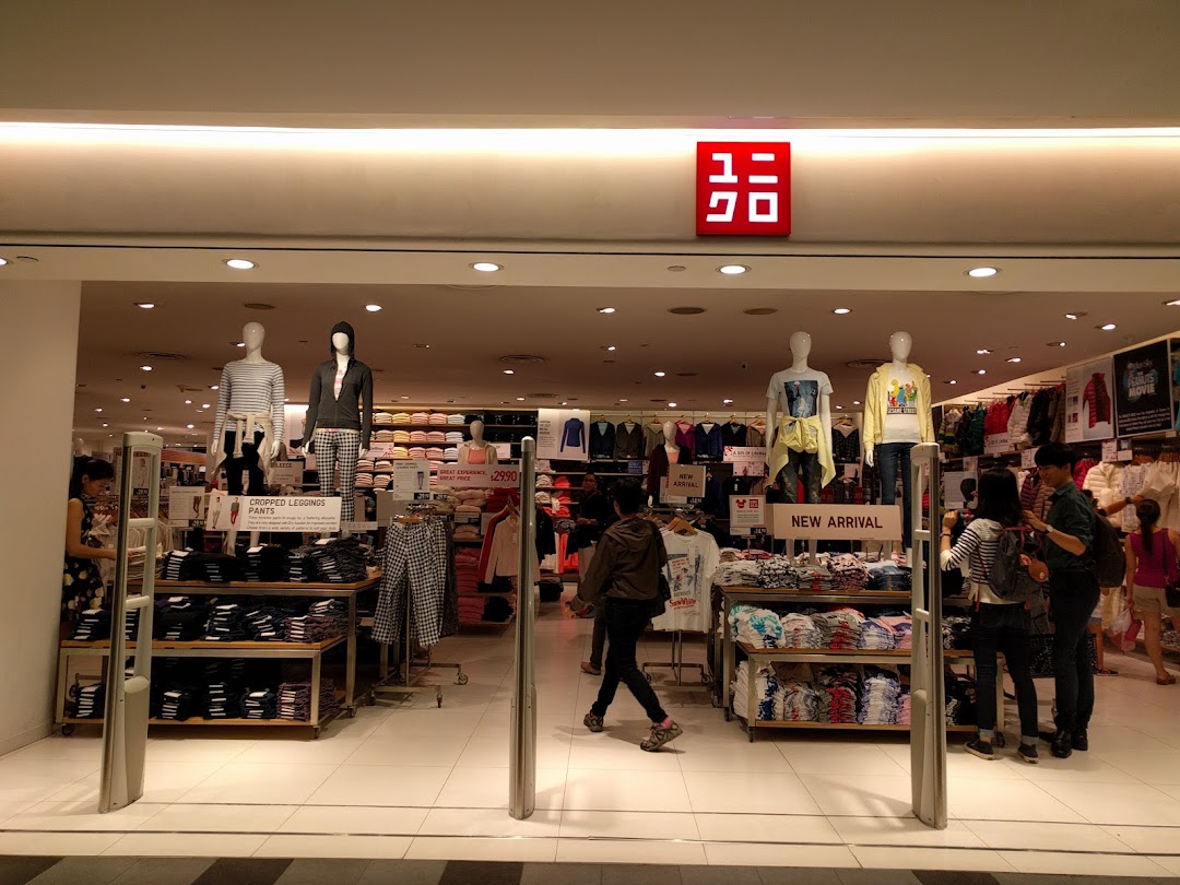 The brightly lit entrance of a UNIQLO store, showcasing mannequins and new apparel displays.
