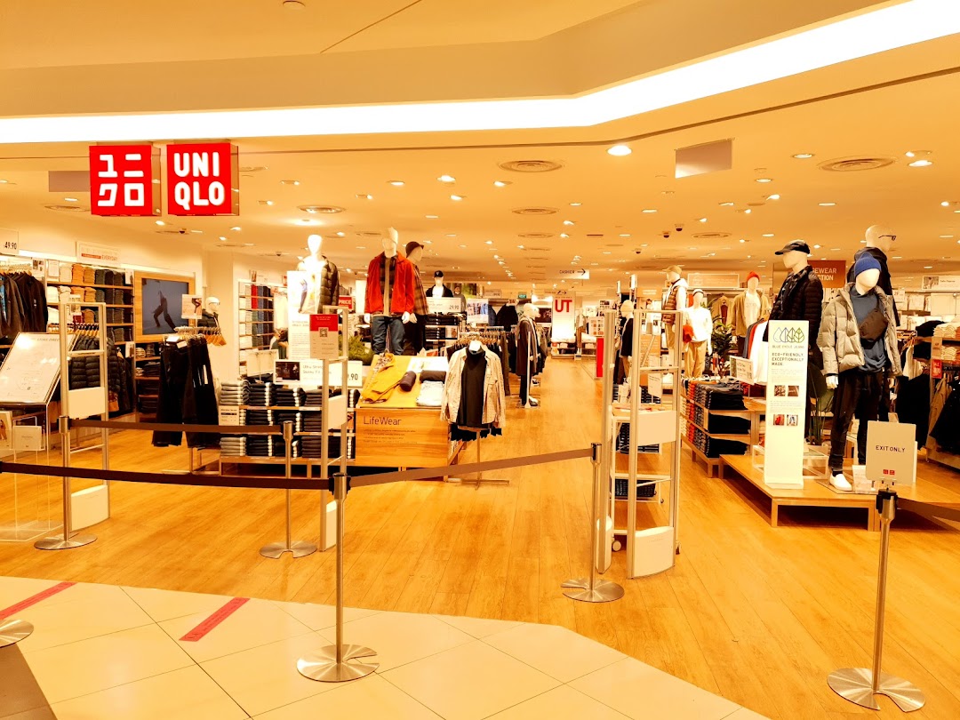 Interior view of a brightly lit UNIQLO store showcasing clothing displays and mannequins.