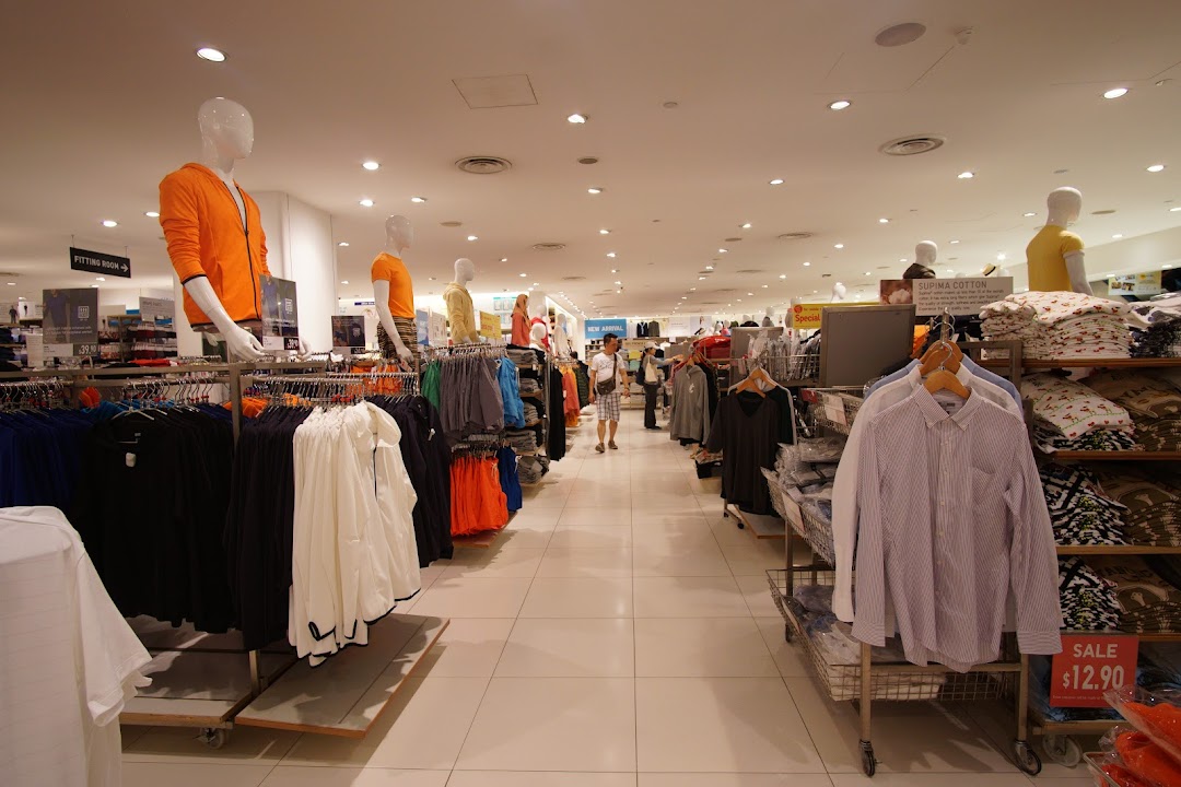 Interior view of a UNIQLO store, showcasing clothing racks, mannequins, and a customer browsing apparel.
