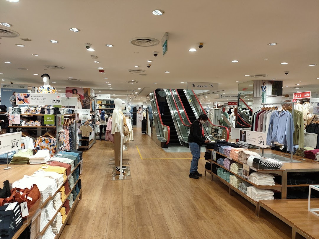 Interior view of UNIQLO showcasing clothing displays, mannequins, and an escalator leading to other departments.