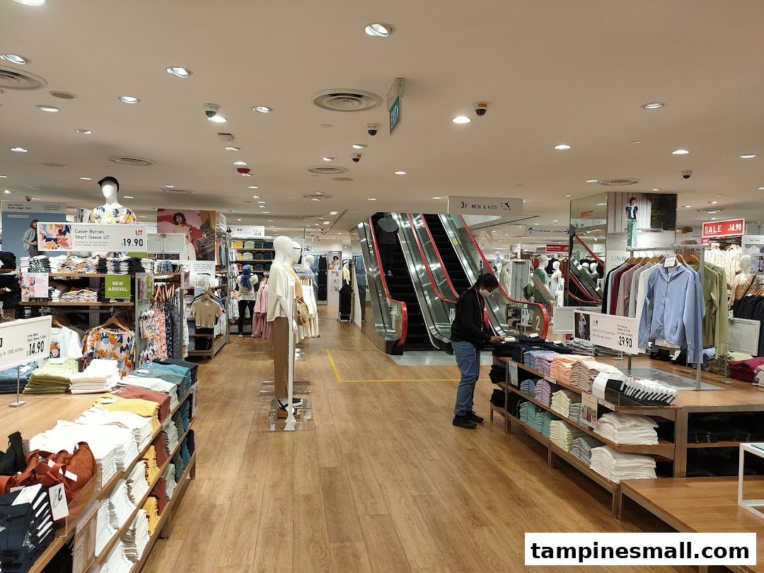 Interior view of UNIQLO showcasing clothing displays, mannequins, and an escalator leading to other departments.