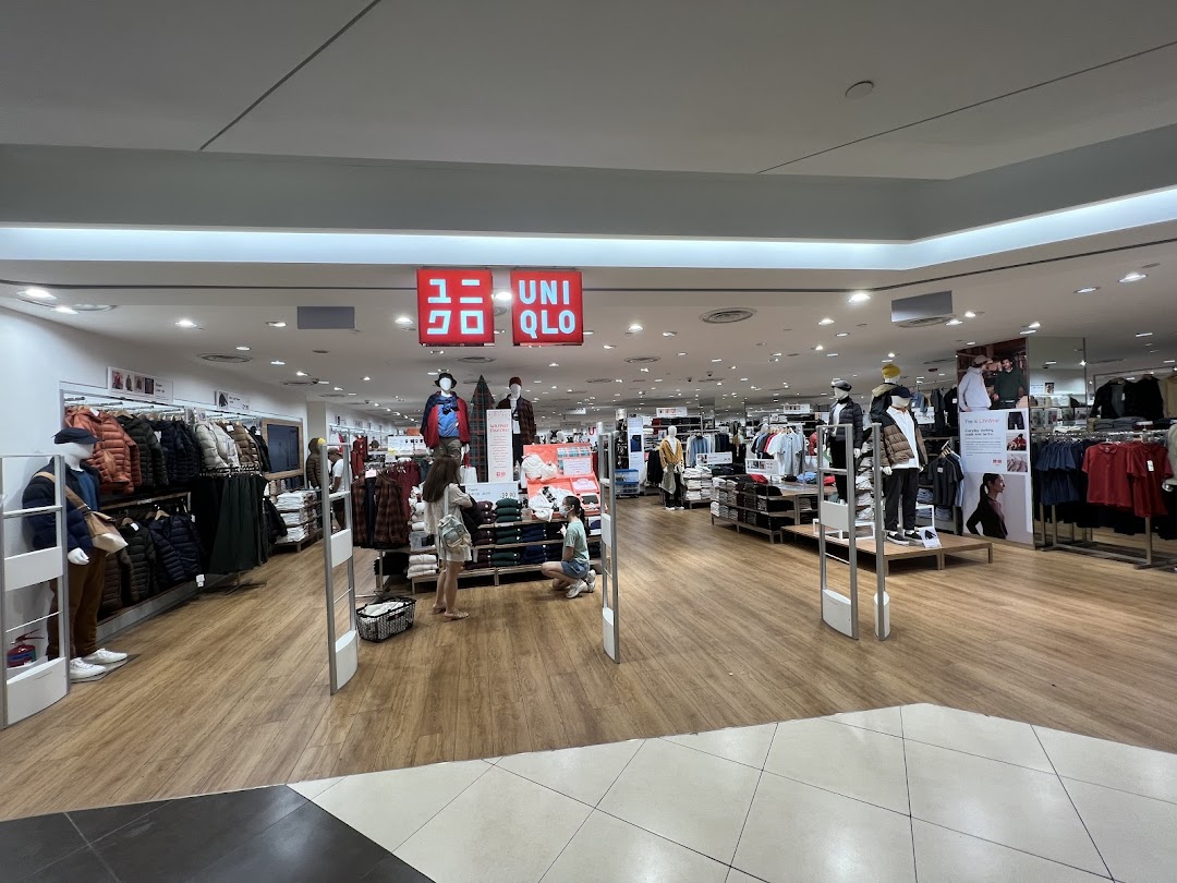 View of the UNIQLO store entrance with clothing displays and shoppers inside.