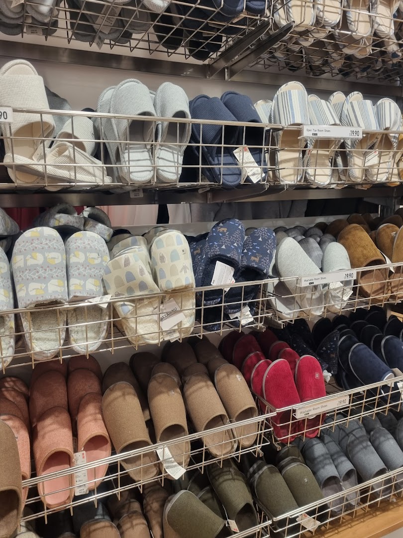 Shelves filled with a wide variety of comfortable room shoes and slippers in different colors and styles.