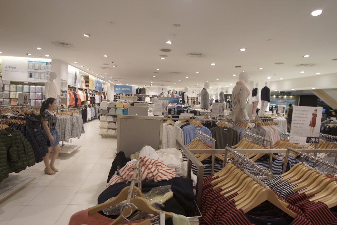 Interior view of UNIQLO store showcasing clothing racks, mannequins, and a customer browsing apparel.