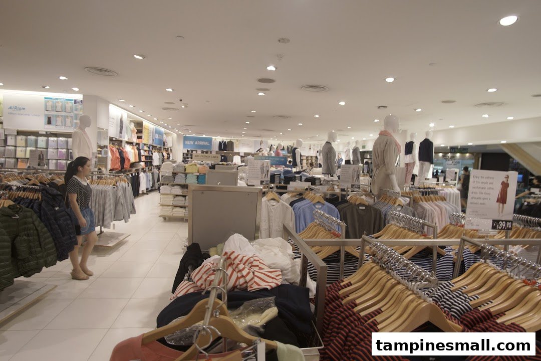 Interior view of UNIQLO store showcasing clothing racks, mannequins, and a customer browsing apparel.