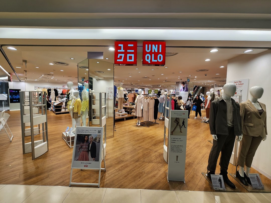 The brightly lit entrance of UNIQLO at Tampines Mall, showcasing mannequins and a wide range of apparel.