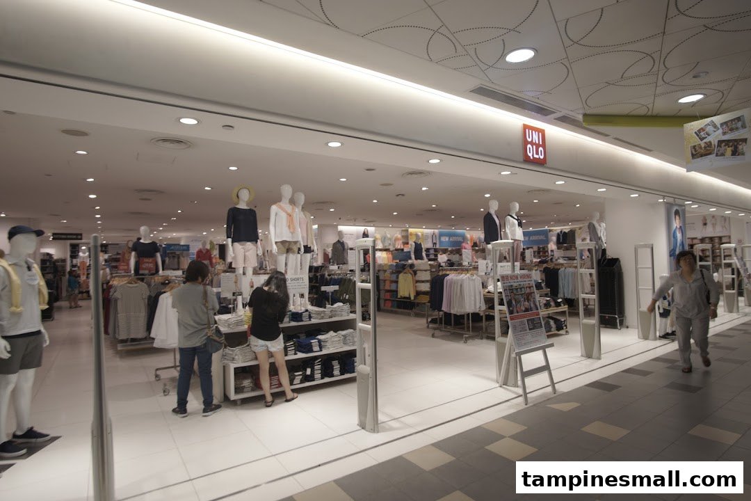 The UNIQLO store entrance at Tampines Mall, showcasing apparel on mannequins and customers browsing.