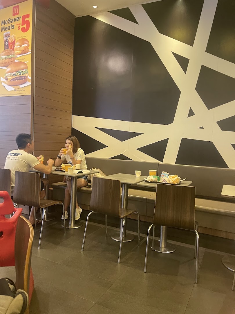Customers enjoy meals in a brightly lit McDonald's dining area with a McSaver Meals poster.