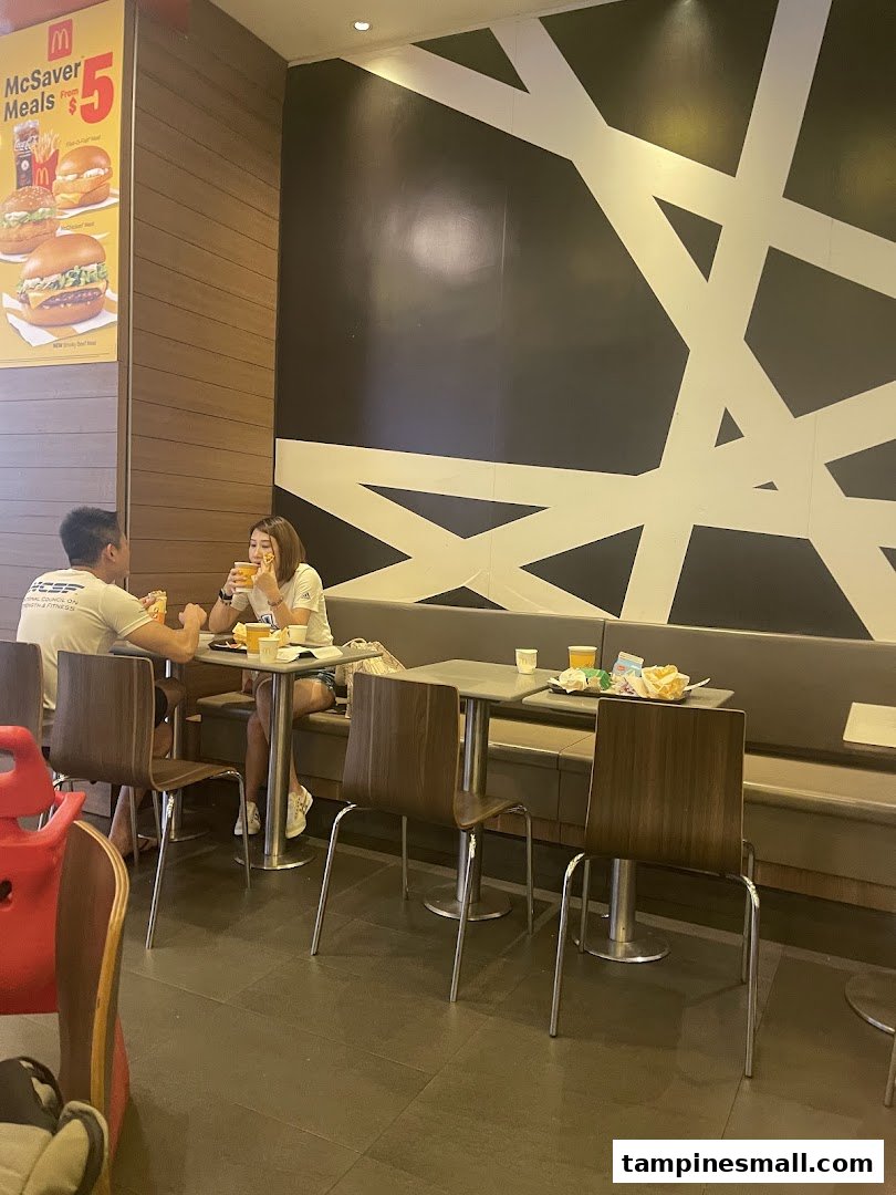 Customers enjoy meals in a brightly lit McDonald's dining area with a McSaver Meals poster.
