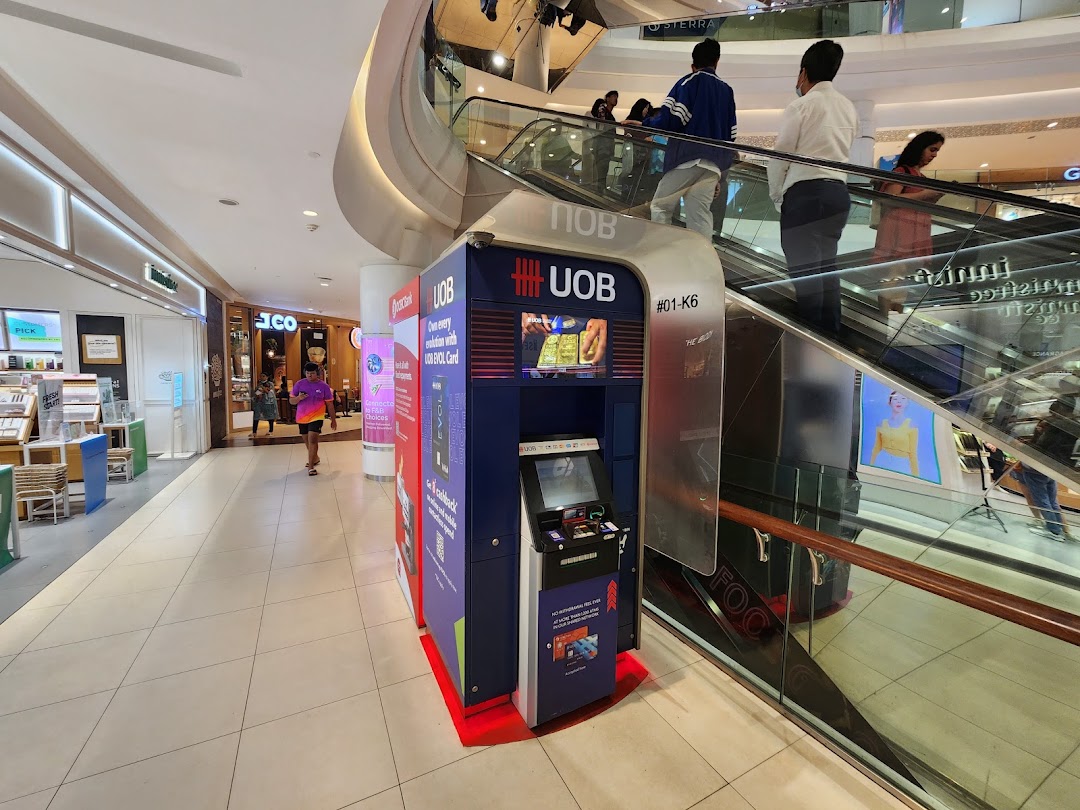 A UOB ATM conveniently located next to an escalator in Tampines Mall, offering essential banking services.