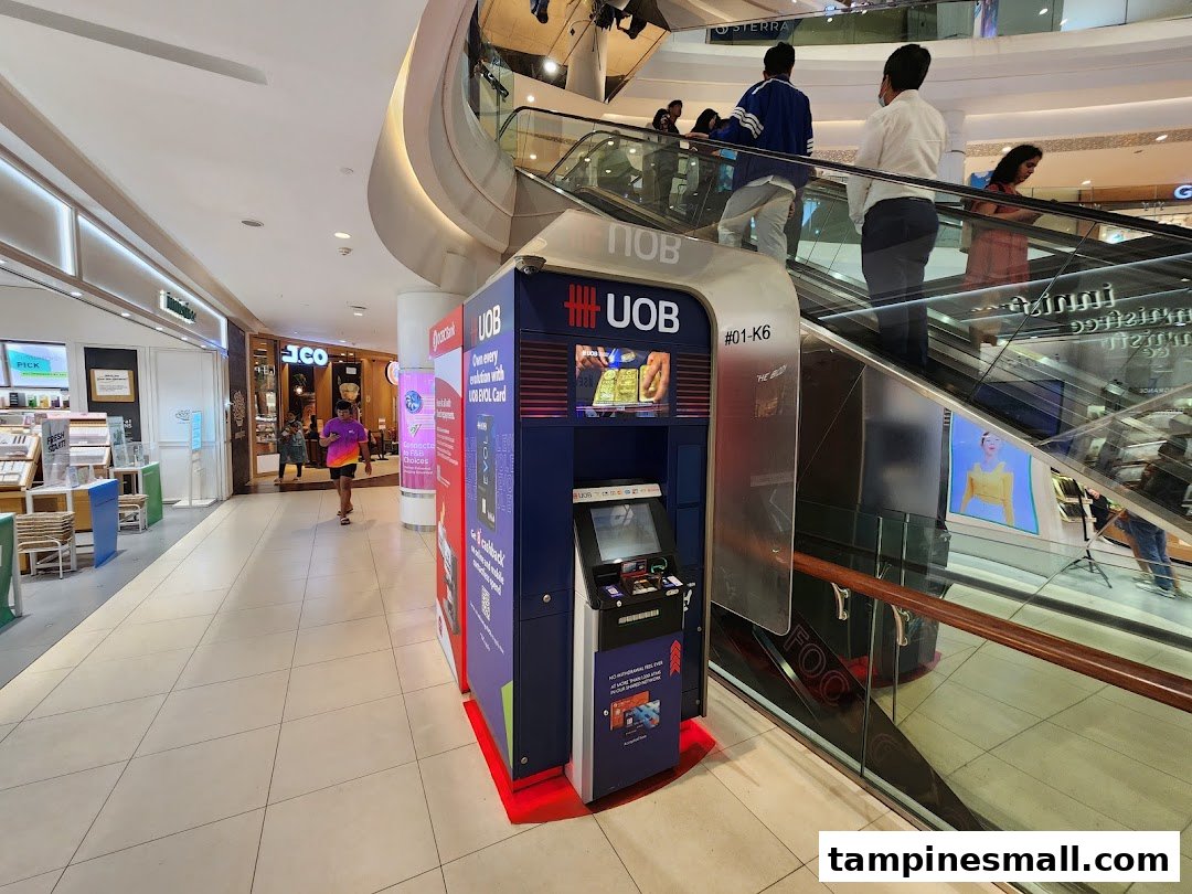 A UOB ATM conveniently located next to an escalator in Tampines Mall, offering essential banking services.