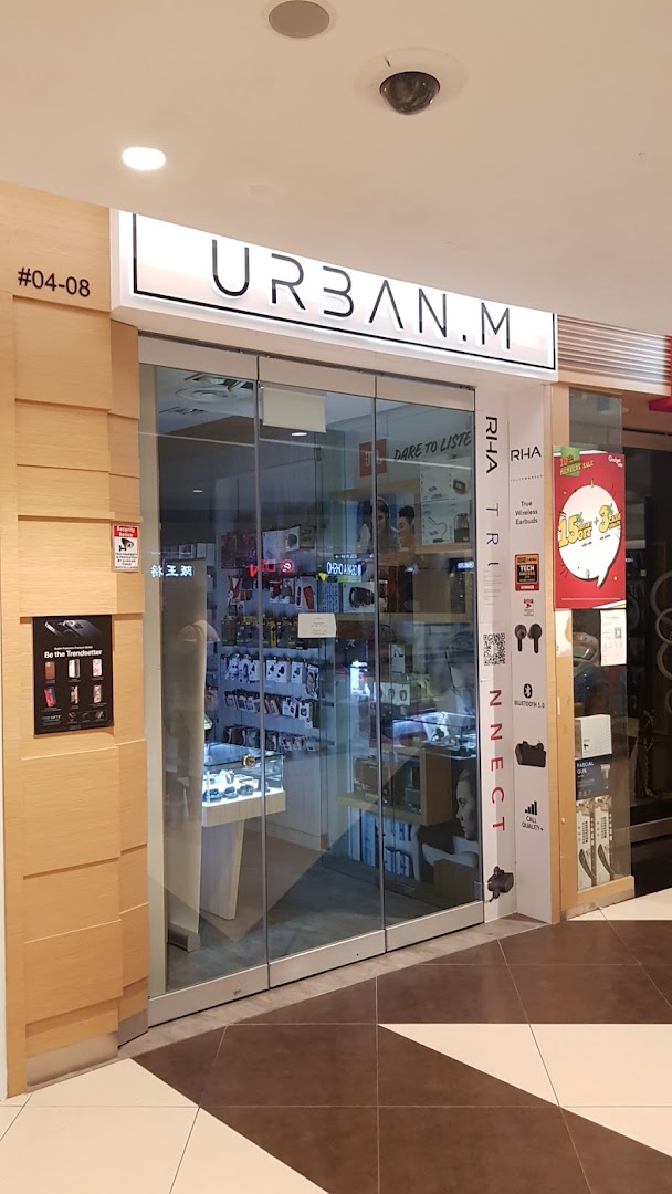 The shop front of URBAN.M, featuring a glass entrance and displays of electronic accessories.