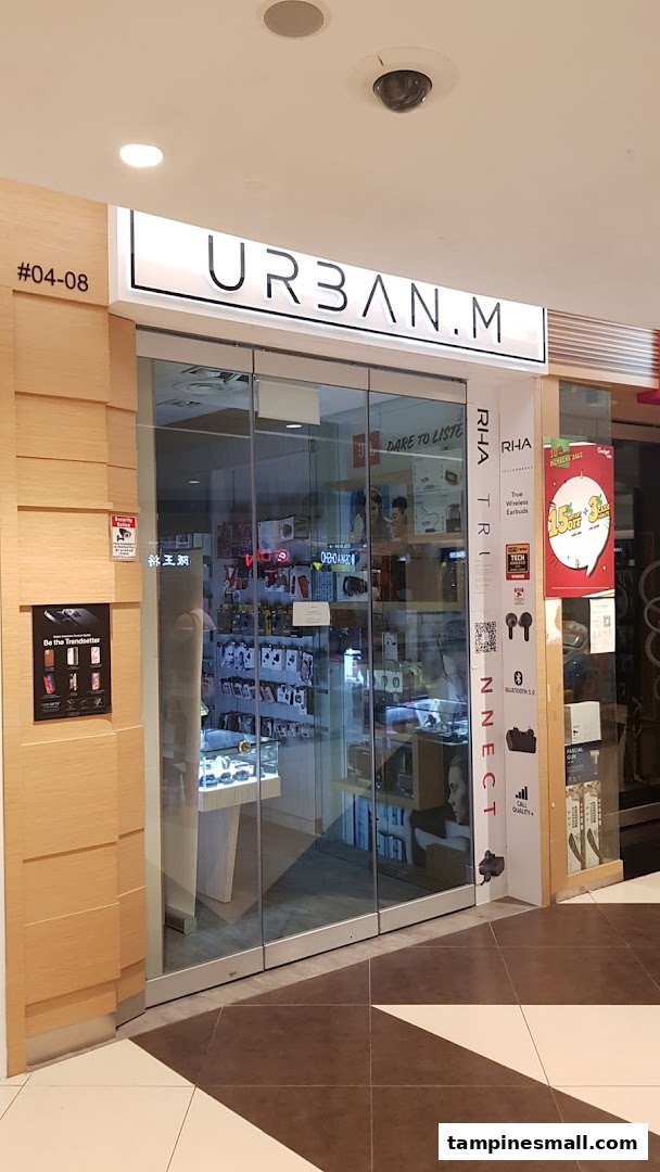 The shop front of URBAN.M, featuring a glass entrance and displays of electronic accessories.