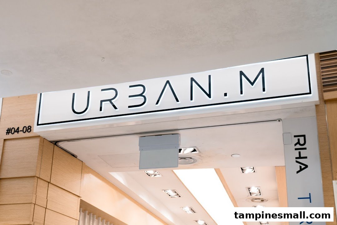 An illuminated 'URBAN.M' sign above a modern shop entrance, with store number #04-08 visible.