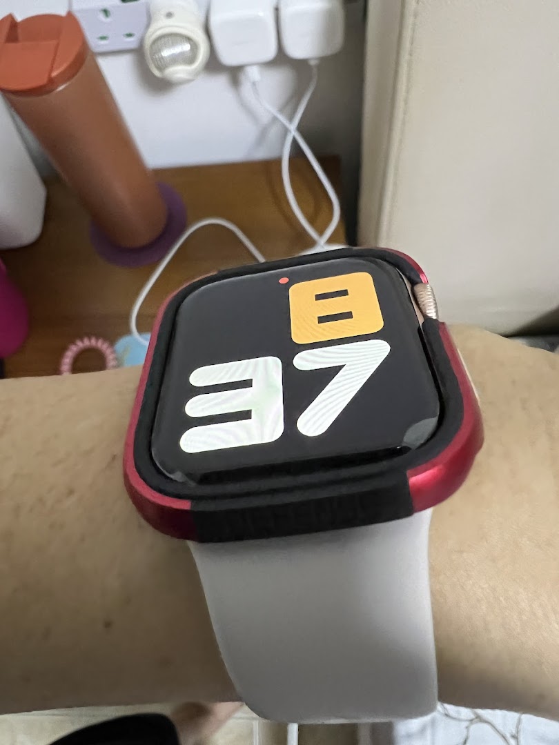 A close-up of a smartwatch with a red protective case worn on a person's wrist.
