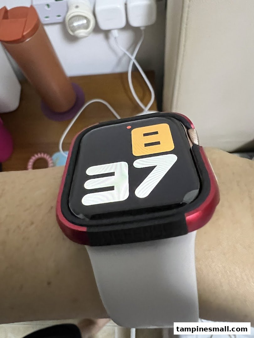 A close-up of a smartwatch with a red protective case worn on a person's wrist.