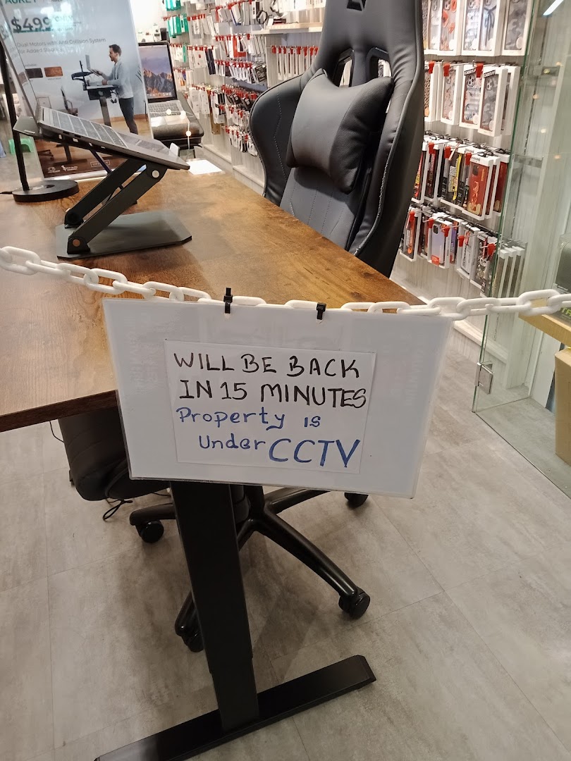 An interior view of URBAN.M, featuring tech accessories, a desk setup, and a temporary 'be back soon' sign.