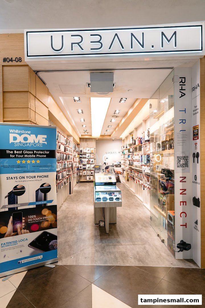 The storefront of URBAN.M, a mobile accessories and electronics shop, featuring product displays and a glass protector banner.