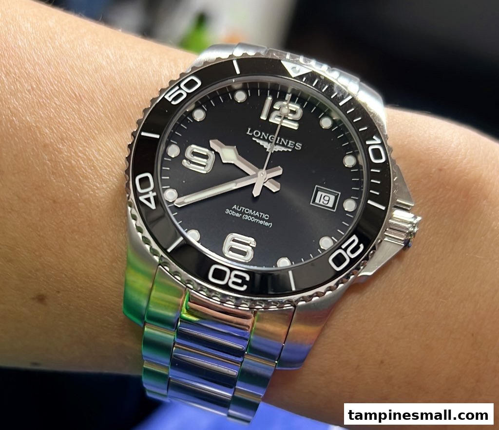 A close-up of a Longines automatic dive watch with a black dial and steel bracelet on a wrist.