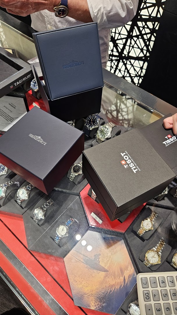 Luxury watch boxes from Longines and Tissot displayed on a counter with various watches.