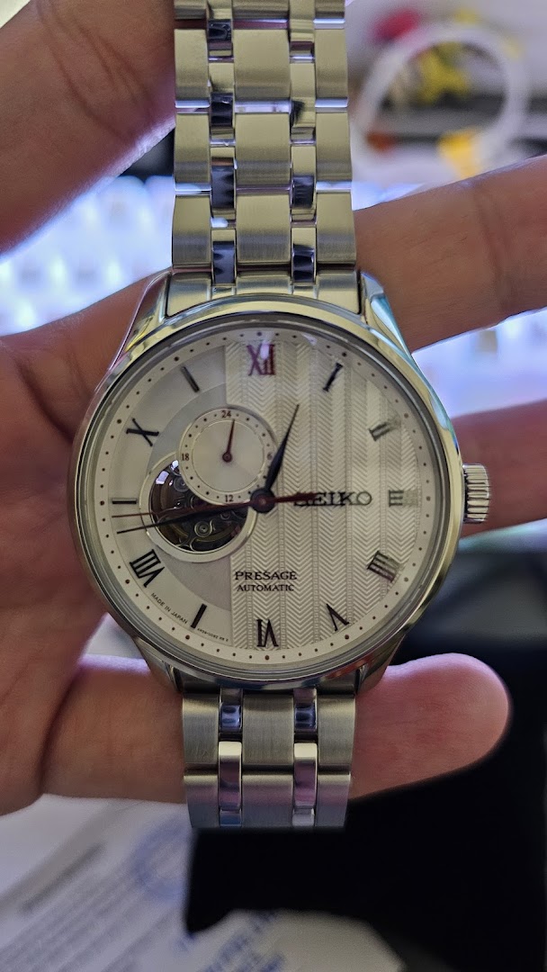 Close-up of a silver Seiko Presage automatic watch with a white textured dial and open heart complication.
