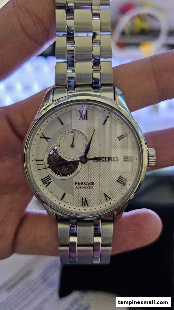 Close-up of a silver Seiko Presage automatic watch with a white textured dial and open heart complication.