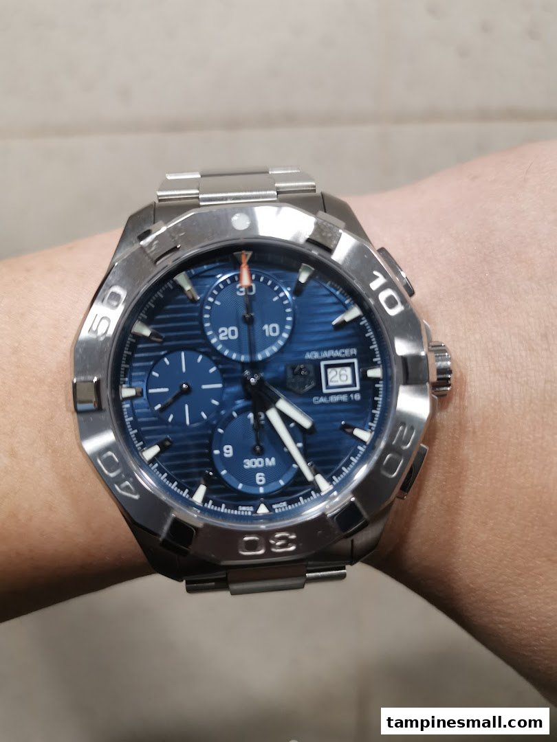 A close-up of a TAG Heuer Aquaracer watch with a blue dial and steel bracelet on a person's wrist.