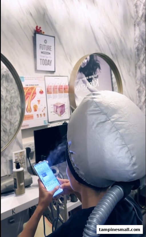 A customer relaxing during a hair treatment with a steamer at Vintage Studio VS Salon.