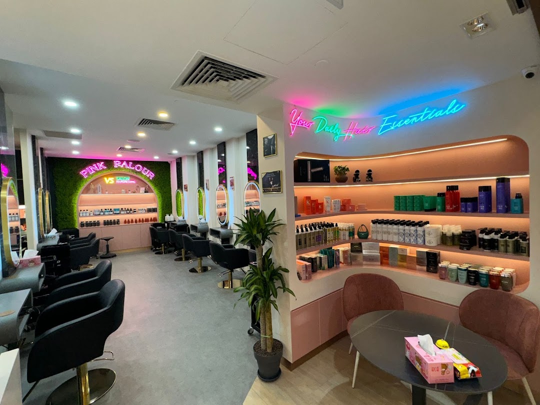 A vibrant, modern hair salon interior featuring styling stations, product displays, and neon signs.