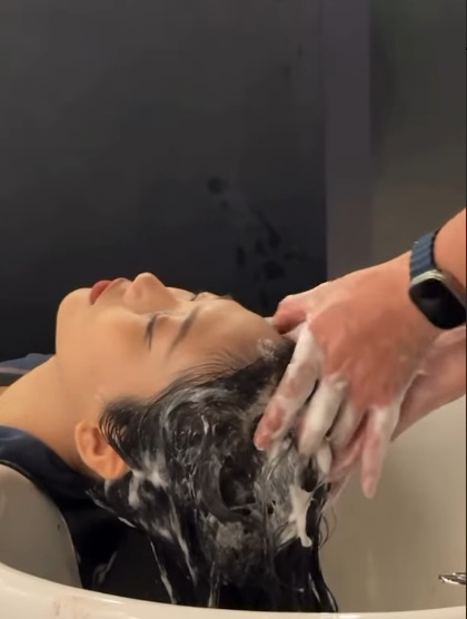 A customer receives a relaxing hair wash service at a salon.