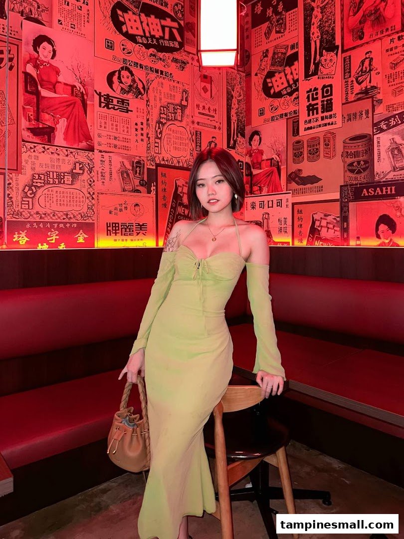A person in a light green dress poses inside a salon with vintage Chinese-themed decor and red lighting.