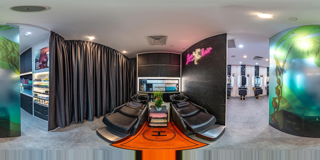 A panoramic interior view of a modern hair salon featuring wash basins and styling stations.