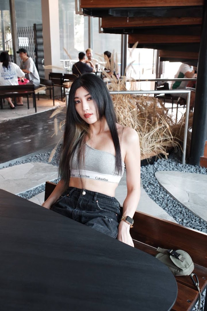 A woman sits at a table in a modern, stylish interior with other patrons in the background.