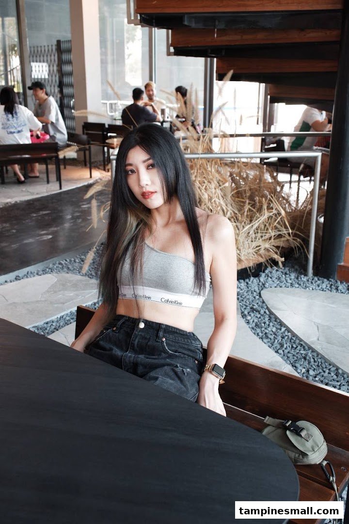 A woman sits at a table in a modern, stylish interior with other patrons in the background.
