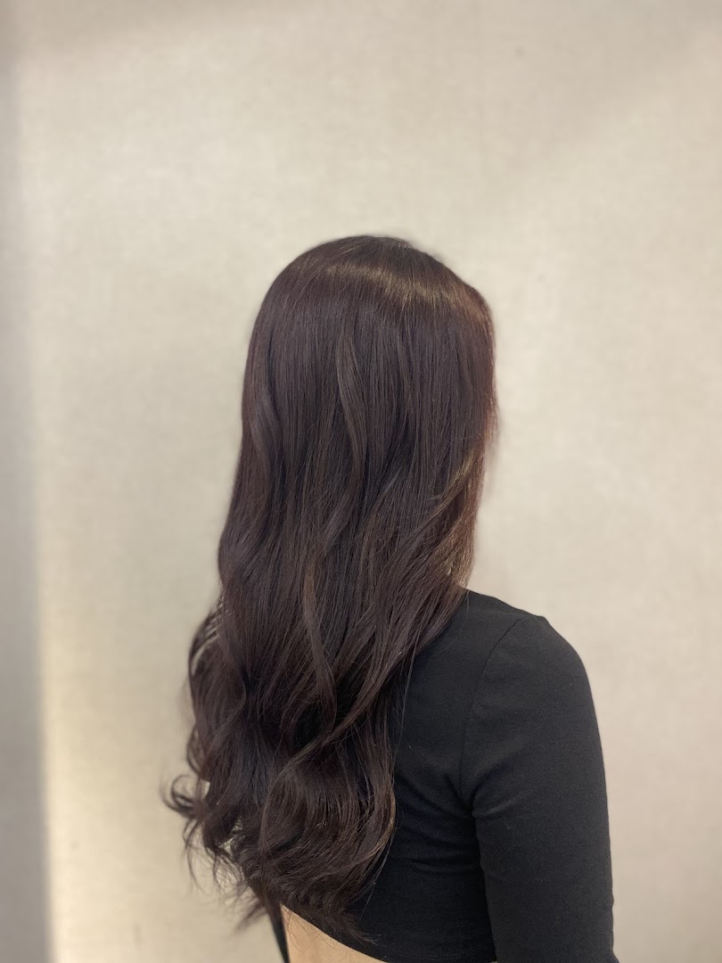 A person's back view showcasing long, dark, wavy hair, likely after a salon treatment.
