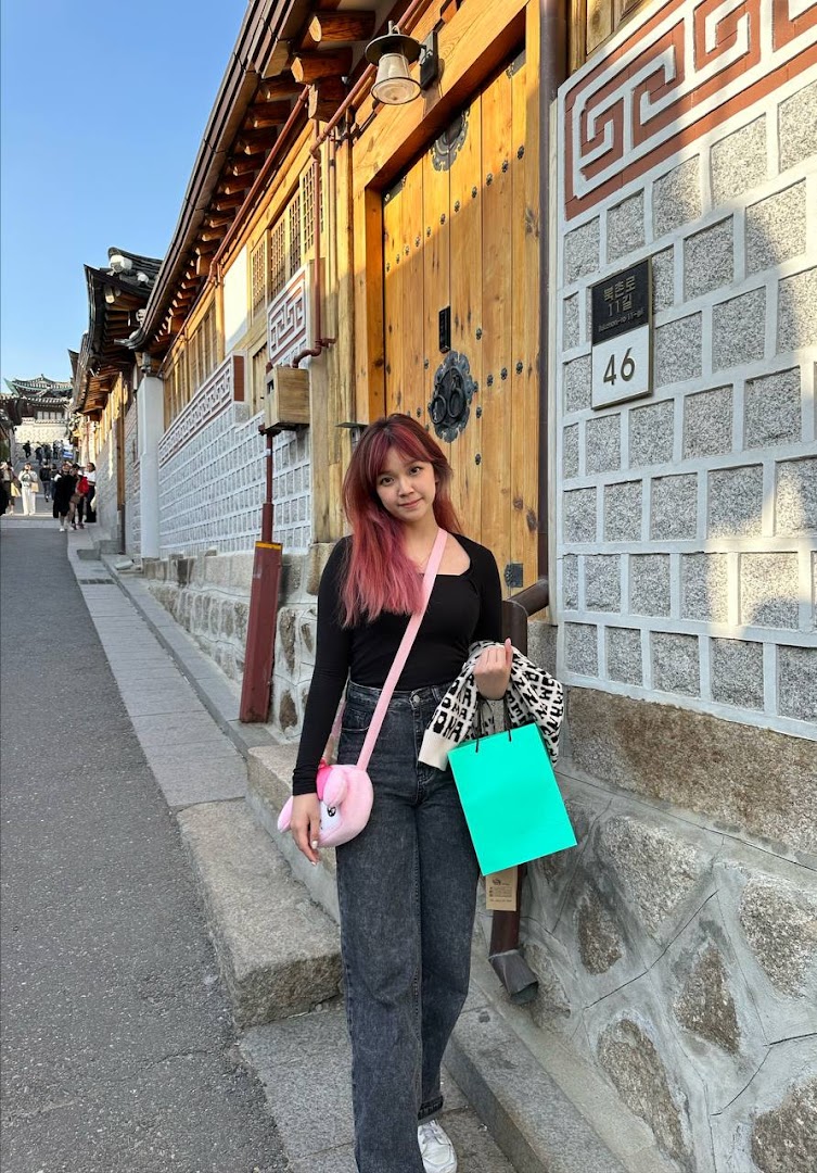 A stylish woman with vibrant pink hair enjoys a day out, showcasing her unique look.