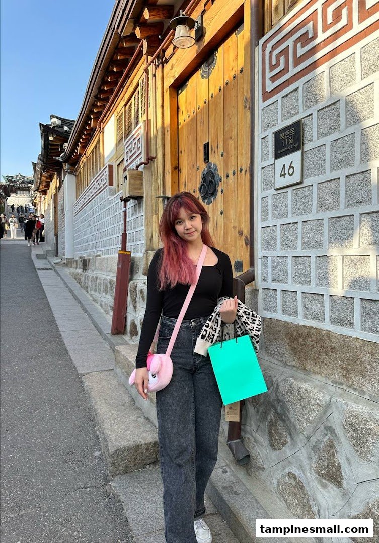 A stylish woman with vibrant pink hair enjoys a day out, showcasing her unique look.