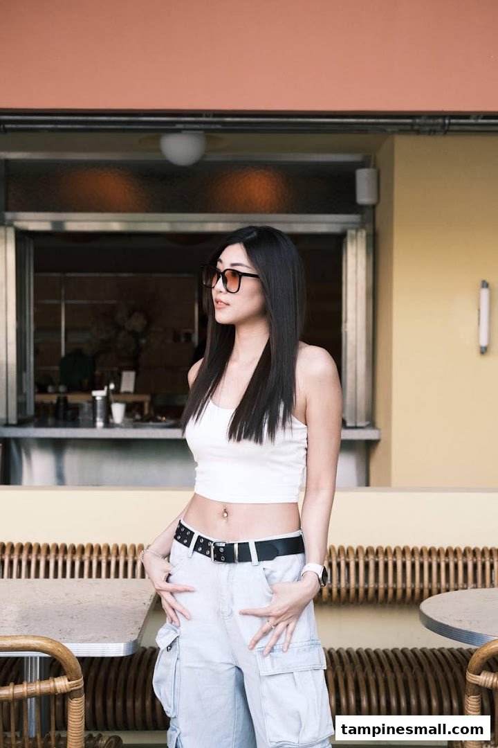 A stylish woman stands outside a modern salon or studio, featuring outdoor seating.