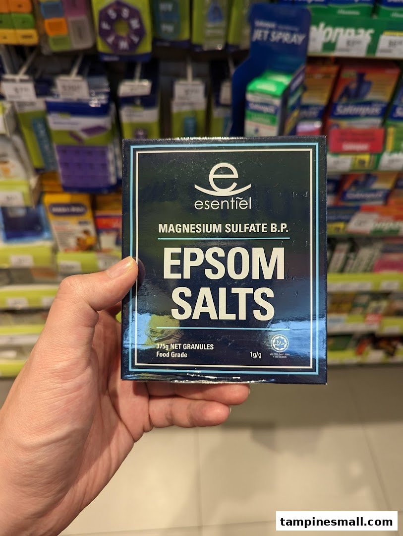 A hand holds a box of Esentiel Epsom Salts (Magnesium Sulfate) inside a Watsons pharmacy.