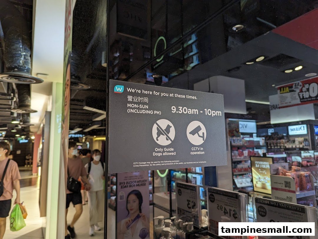 A view of the Watsons store entrance at Tampines Mall, displaying operating hours and store policies.