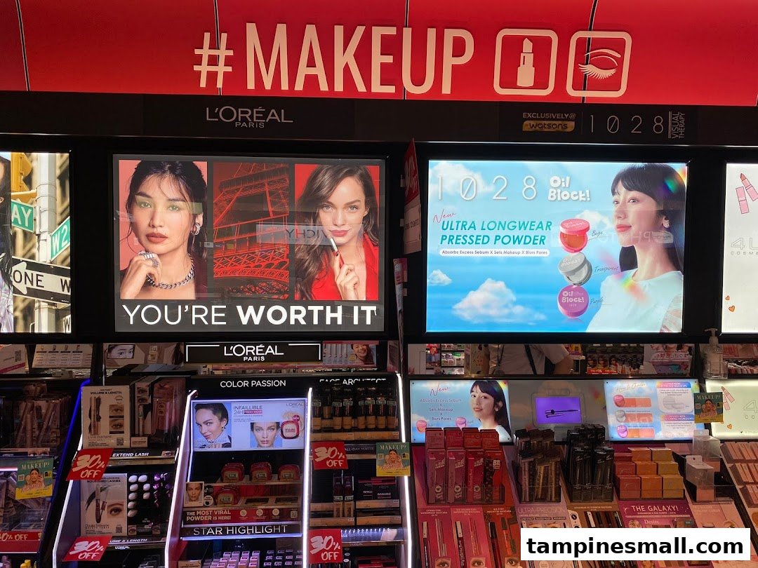 A vibrant makeup section inside Watsons, featuring L'Oréal and 1028 product displays and digital advertisements.