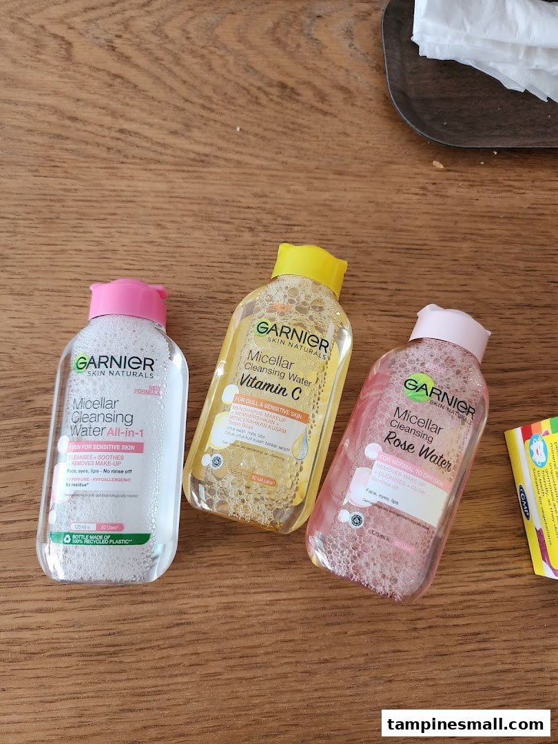 Three bottles of Garnier Micellar Cleansing Water on a wooden surface.
