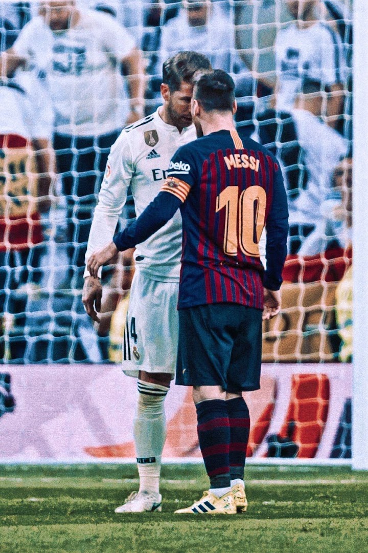 Two legendary football players, Lionel Messi and Sergio Ramos, face each other on a soccer field.