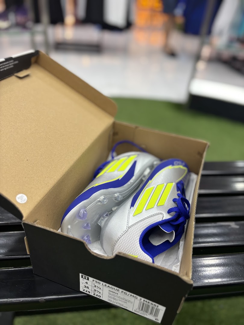 A pair of new silver, blue, and neon yellow soccer cleats in an open box.