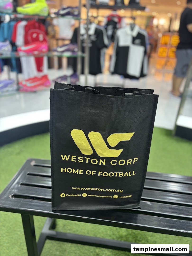 A black Weston Corp shopping bag with 'Home of Football' branding, in a sports retail store.