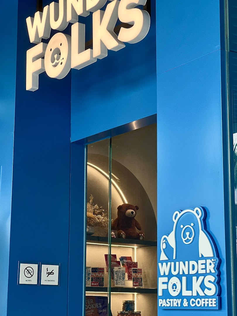 The vibrant blue exterior of Wunderfolks Pastry & Coffee, featuring its distinctive bear logo and display window.